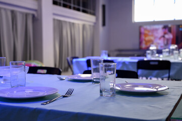 Table setting with white plates and glasses on a blue tablecloth