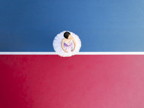 Aerial view of a ballerina in a white tutu, a stark contrast against the vibrant red and blue backdrop, creating a mesmerizing balance of color and form, Adelaide, South Australia, Australia.