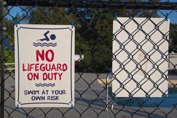 No lifeguard sign on a pool fence