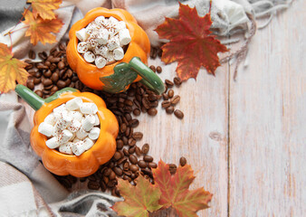 Pumpkin mugs with marshmallows, coffee beans, autumn leaves