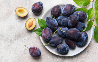 Fresh ripe plums, whole and halved on plate