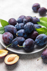 Fresh ripe plums, whole and halved on plate