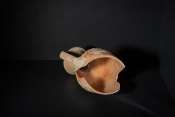 Broken ancient amphora on black background.
