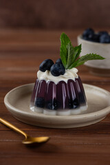 Jelly with fresh blueberries, mint, anchan tea and cream with agar agar with golden spoon on a wooden table. Summer dessert, gelatin free. Vertical orientation.