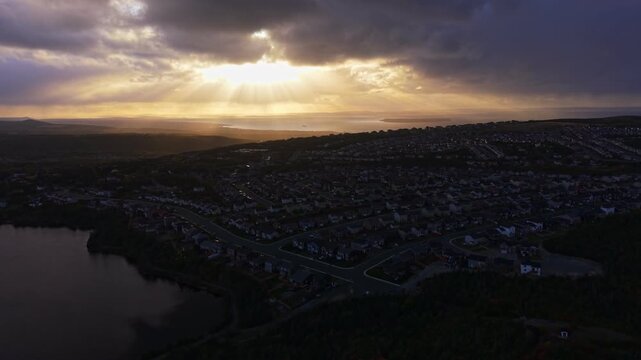 Striking aerial footage of Conception Bay, Newfoundland, capturing god rays breaking through clouds and casting light over open water. Dark sea contrasts with luminous sky in an awe-inspiring scene.