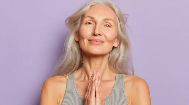Smiling woman with long gray hair, purple background.