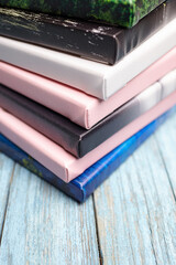 Pile of stretched canvas photo prints in various colors including white, pink, black, and blue, placed on a rustic light blue wooden surface