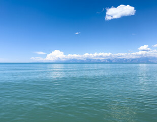 Blue sea water background and sun reflections.. Waves water surface with blue sky and mountain background