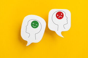 For positive and negative mindset, mental health concept, stress, depression, head with happy and unhappy face on real white speech bubble paper cut on yellow background