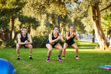 Group training doing squats in sunny park