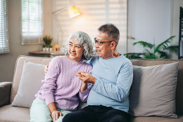 Asian Senior Couple Relaxing on Sofa at Home Sharing Love and Happiness Together Elderly People Enjoying Retirement and Family Bonding