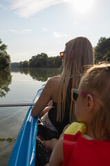 Mother and daughter kayaking on calm river on a sunny summer day, enjoying outdoor adventure and family time together in nature