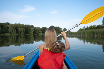 Mother and daughter kayaking on calm river on a sunny summer day, enjoying outdoor adventure and family time together in nature