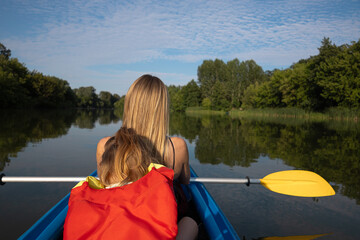 Mother and daughter kayaking on calm river on a sunny summer day, enjoying outdoor adventure and family time together in nature