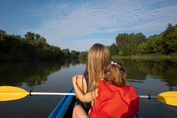 Mother and daughter kayaking on calm river on a sunny summer day, enjoying outdoor adventure and family time together in nature