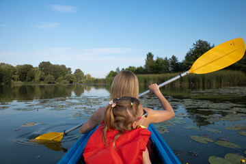 Mother and daughter kayaking on calm river on a sunny summer day, enjoying outdoor adventure and family time together in nature
