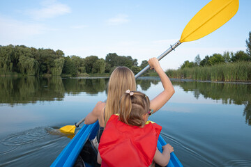 Mother and daughter kayaking on calm river on a sunny summer day, enjoying outdoor adventure and family time together in nature