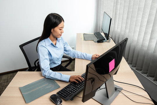 Female programmer using multiple monitor screen to typing HTML data code on keyboard for new website project
