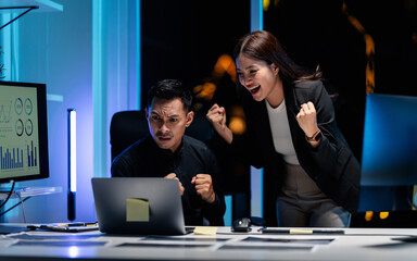 Excited business team celebrates investment success working late night in modern office financial market analysis technology achievement