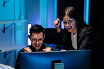 Excited adult colleagues celebrating stock market success or tech breakthrough late night working intense coding session achievement