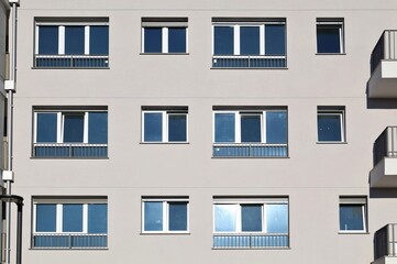 Gray modern residential building facade with PVC windows. Front view, texture.