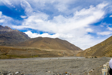 Breathtaking landscape of arid mountains under a blue sky with clouds in Mustang, Nepal. Perfect for travel blogs, adventure magazines, tourism promotion, and educational content.