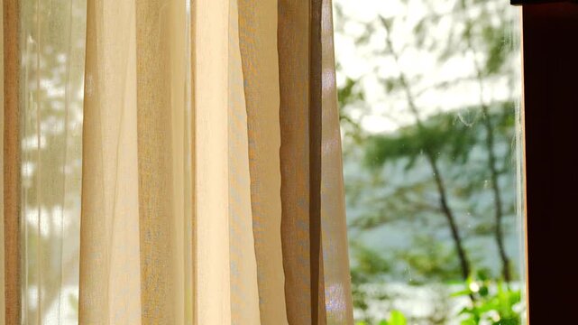 opened the curtains on the window. There was morning light through the window in her room, looking at the view of the mountains and trees as the sun rose	