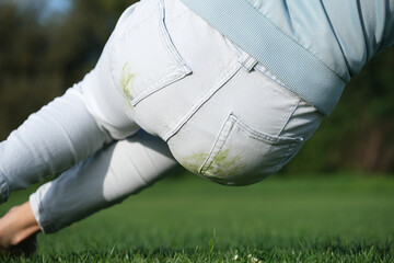 A person turned back falling on green grass wearing white jeans, low angle from below. Outdoor...