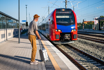 Senior man is arriving at railway station and is ready to board the train. Senior people traveling.
