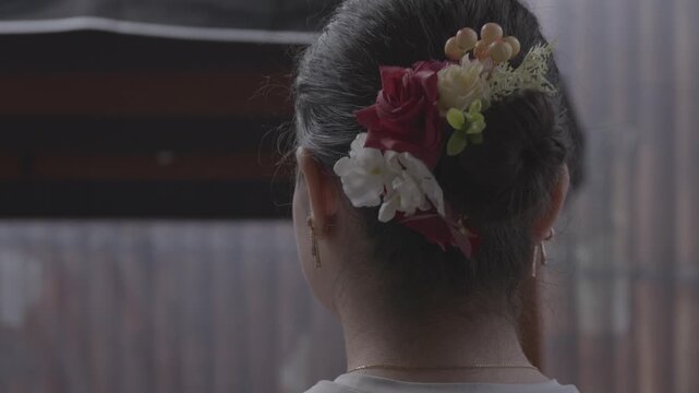 A pensive woman with flowers in her hair walks to a porch swing and sits down to think. This ungraded LOG footage is perfect for a poignant, emotional scene.