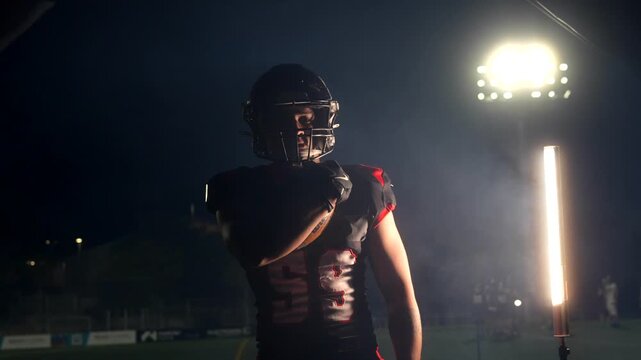 American football player catching and throwing ball at night