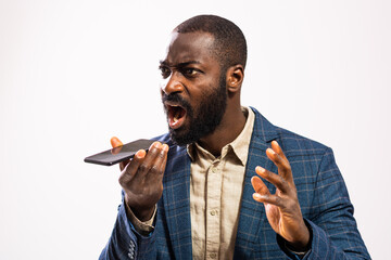 Close up portrait of angry African-american businessman who is talking on mobile phone and threatens.