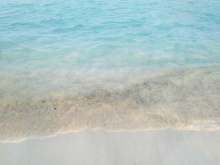 View of blue ocean water splashing the waves on a white sand beach. Water wave photography, beauty of nature. 