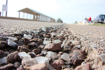 Road edge with loose rocks, shelter in the background, bright day