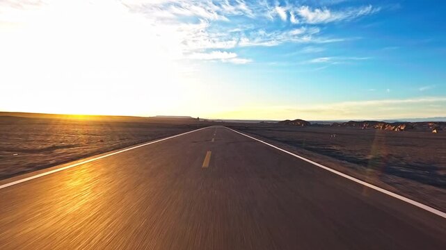 Driving car oxn asphalt road stretching through a vast desert landscape towards the horizon at sunset