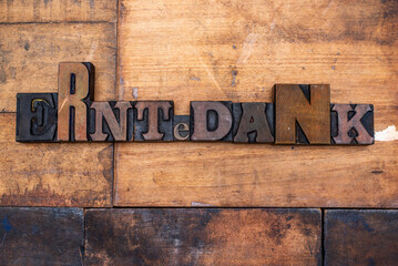Das Wort Erntedank, mit alten Lettern aus Holz, auf einem Altholzuntergrund ausgelegt.