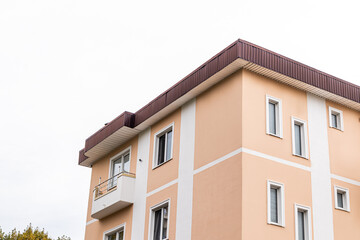 The corner of the stylish house is beige with modern white decor and narrow windows. a fragment of the last floors of the house. urban architecture