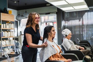 Hairdresser preparing a young woman's wet hair for a beauty treatment in a modern hairdressing salon