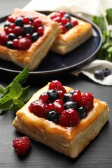 Tasty puff pastries with berries and mint on grey wooden table, closeup