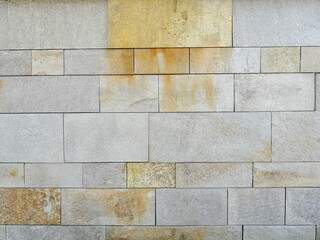 Natural stone facade with smooth slabs and yellowish-brown discoloration. Close-up. Copyspace.