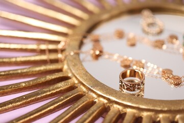 Stylish gold jewelry on violet background, closeup