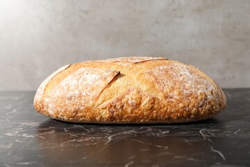 Loaf of fresh bread on black marble table, closeup