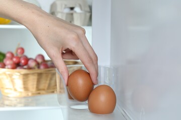 Woman taking raw chicken egg from fridge, closeup © New Africa