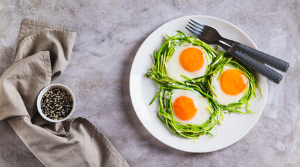 Fried eggs in zucchini noodle nests on a plate on the table top view web banner