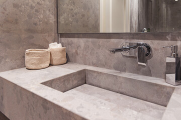 Modern bathroom vanity featuring a natural stone basin, wood shelf, and a mirror. A hair dryer hangs nearby, suggesting full amenities © Igor