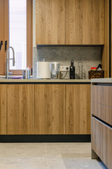 A modern kitchen interior with wooden cabinets, stone backsplash, and small appliances like a toaster and coffee maker