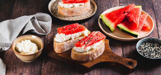 Delicious sandwich with ricotta, watermelon and sesame seeds on a board on the table web banner