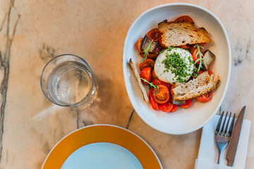 Overhead view of a gourmet burrata salad with cherry tomatoes. A healthy and protein-rich dish emphasizing vegetables and Italian cheese
