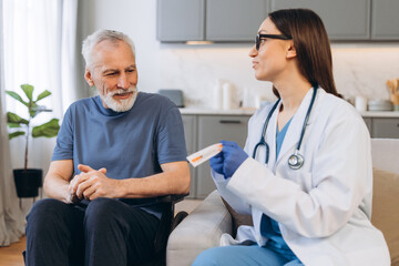 Obraz premium Beautiful female doctor discussing treatment plan with senior patient holding syringe