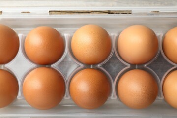 Raw chicken eggs in container on table, closeup